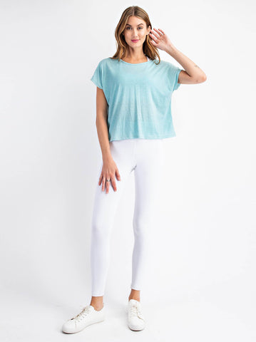 woman standing with a teal top and white leggings